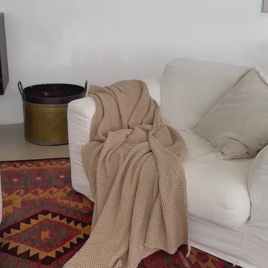 Video som viser beige pledd i lin og bomull på sofa, vaffelvevd og mykt, ideelt for et sunt og bærekraftig hjem