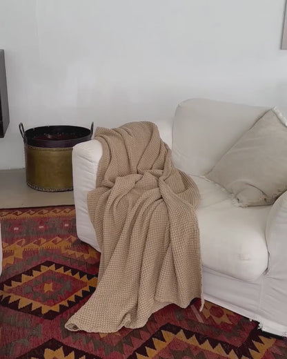 Video som viser beige pledd i lin og bomull på sofa, vaffelvevd og mykt, ideelt for et sunt og bærekraftig hjem