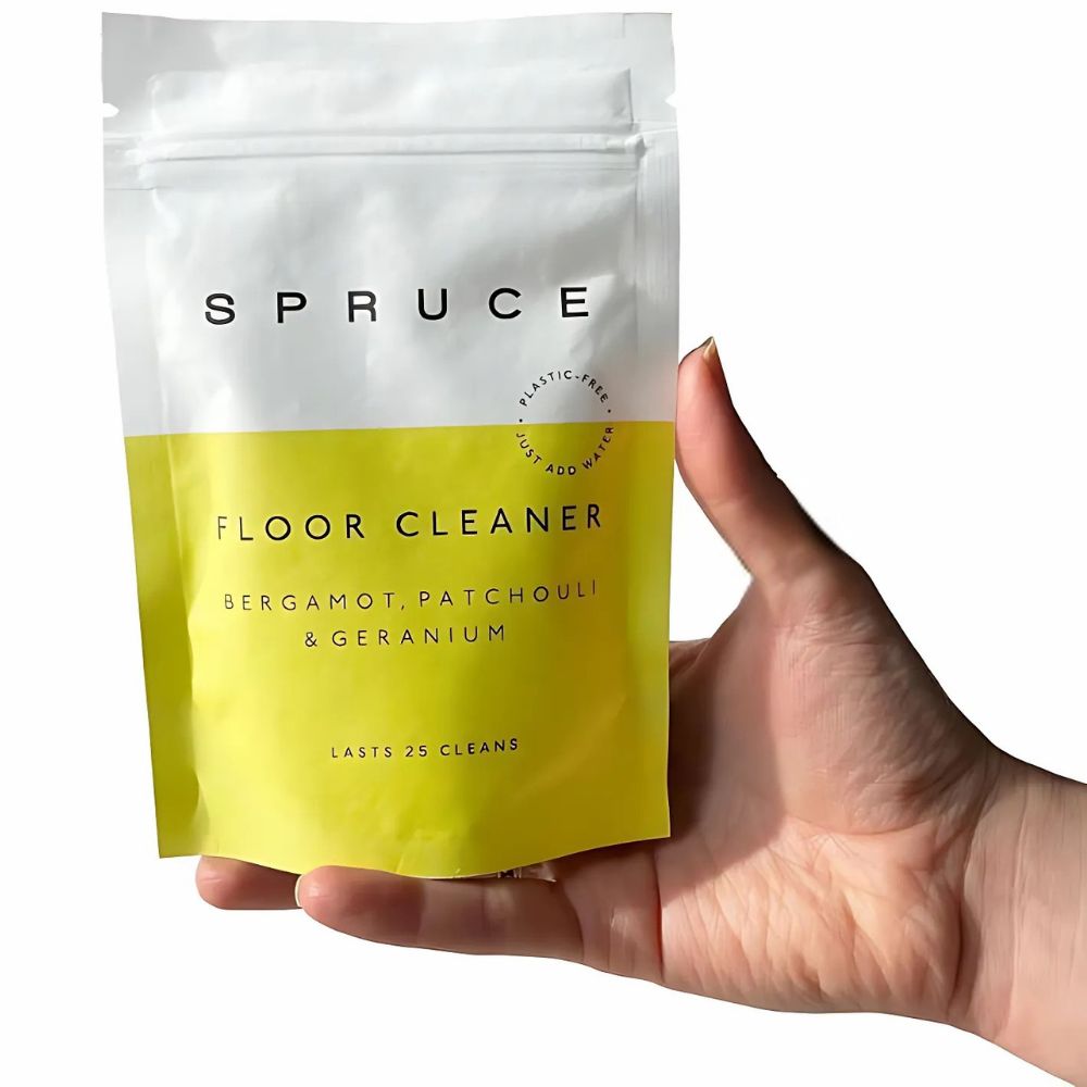 Hånd som holder Spruce gulvvask – et naturlig, plastfritt alternativ for rene gulv uten skadelige kjemikalier.