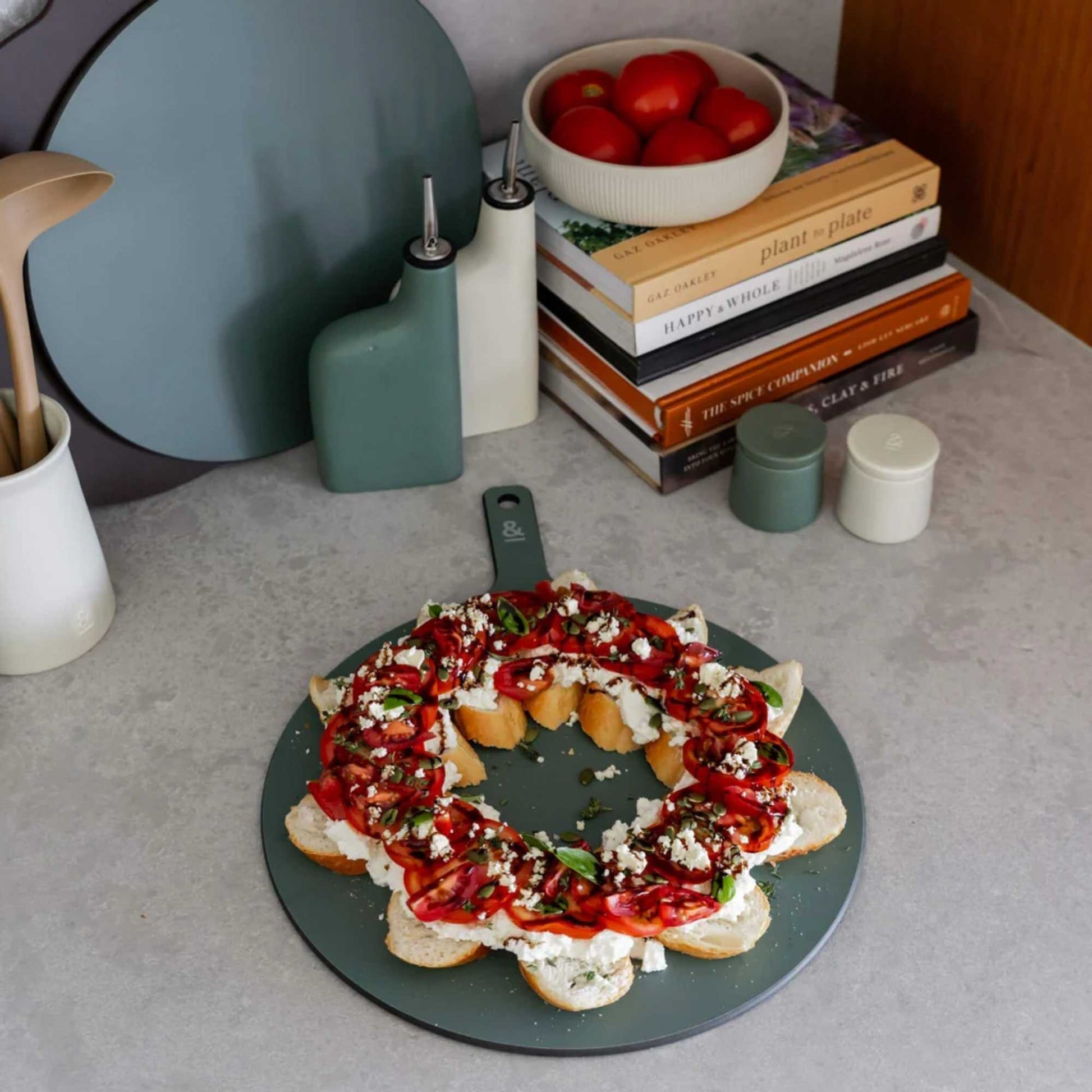 Rund skjærefjøl i trefiber i fargen Eucalyptus brukt til servering av bruschetta på kjøkkenbenk, fra Seed & Sprout