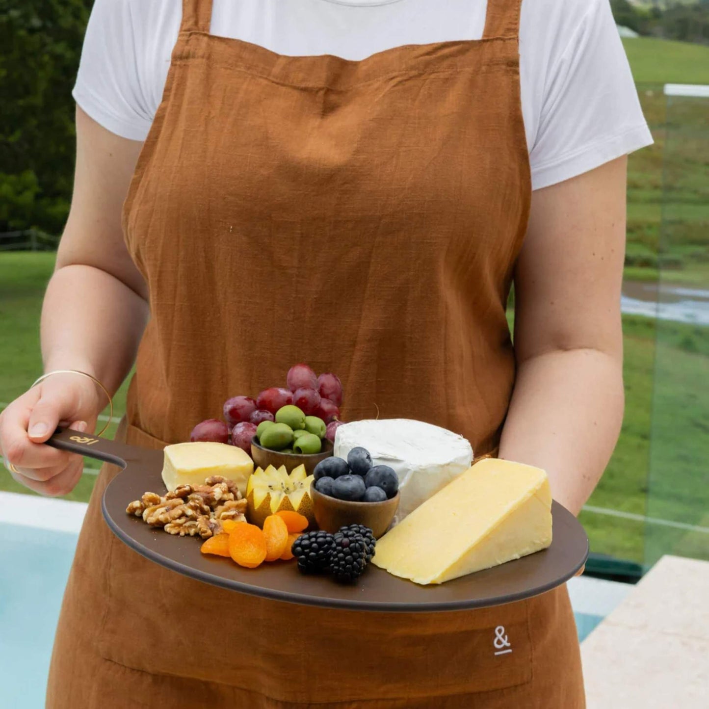 Rund skjærefjøl i trefiber i fargen Nutmeg brukt til servering av ost, nøtter og frukt, fra Seed & Sprout
