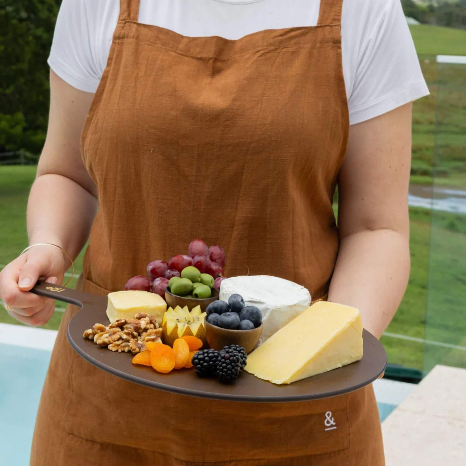 Rund skjærefjøl i trefiber i fargen Nutmeg brukt til servering av ost, nøtter og frukt, fra Seed & Sprout