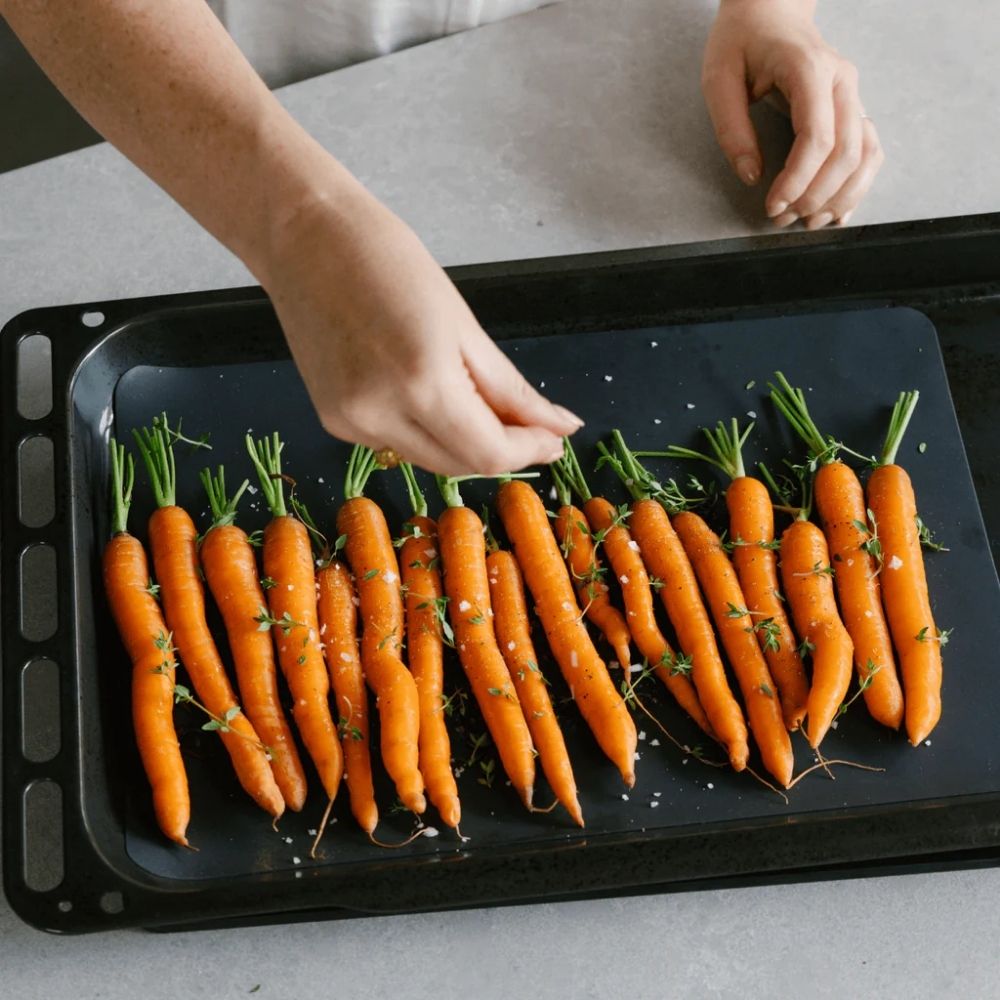 Silikonbakematte i fargen Liquorice med gulrøtter klare for ovnsbaking, et gjenbrukbart og non stick alternativ til engangs bakepapir.