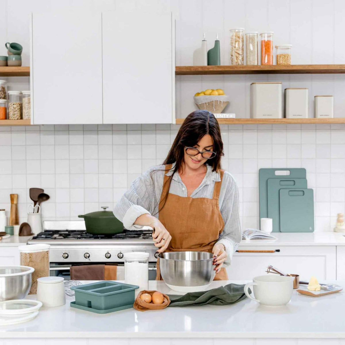 Person lager mat på kjøkken med silikon fryseform på benken, brukt til porsjonering og meal prep.