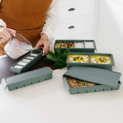 Silikon fryseformer i flere størrelser fylt med ulike retter, vist i bruk under matprep – LFGB-sertifisert silikon fra Seed & Sprout for trygg porsjonsfrysing.