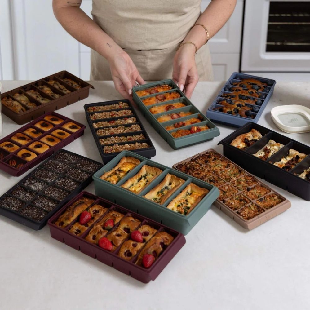 Silikon fryseformer fra Seed & Sprout fylt med ulike porsjoner mat til baking og porsjonsfrysing på kjøkkenbenk.