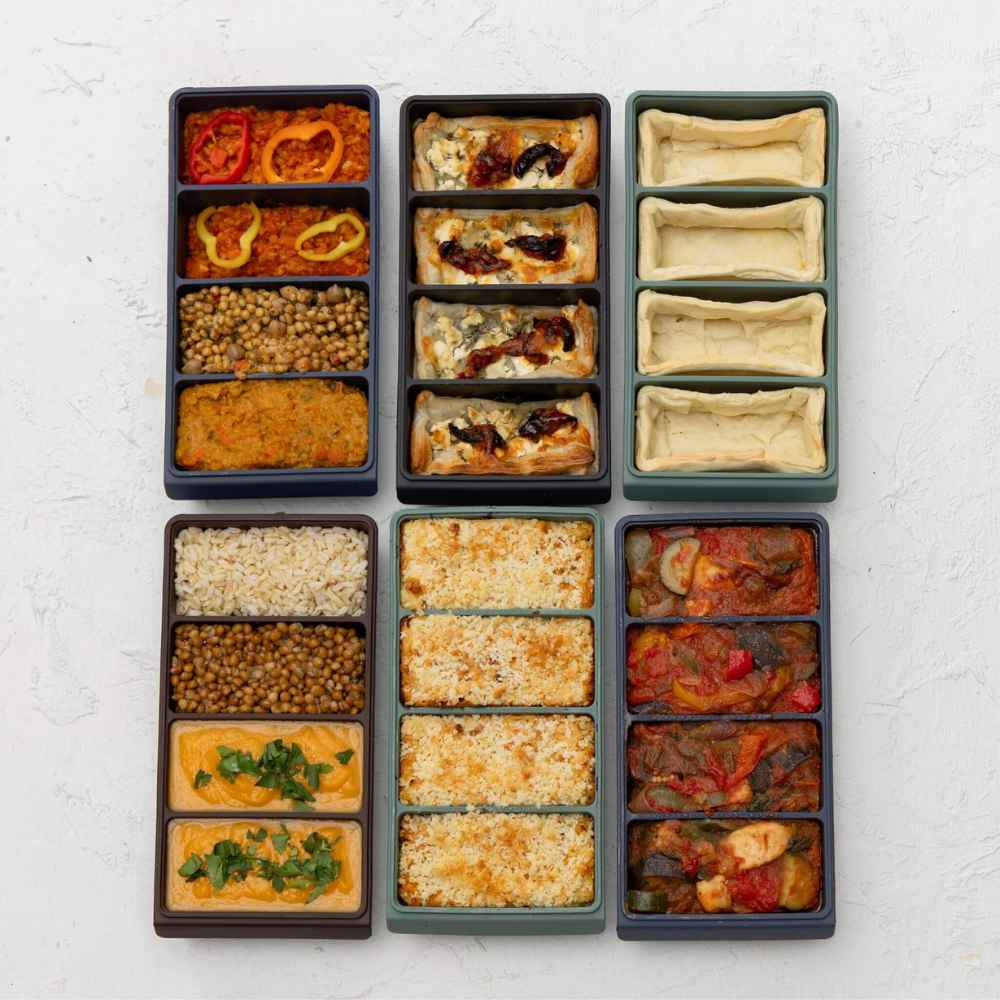 Silikonfryseformer med fire rom fylt med ulike middager og porsjoner til meal prep.