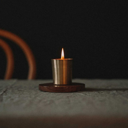 Tent Skär Organics bivokslys i gullfarget holder, stående på treunderlag i et varmt og stemningsfullt rom – håndlaget økologisk bivokslys hos Sunnerhjem.