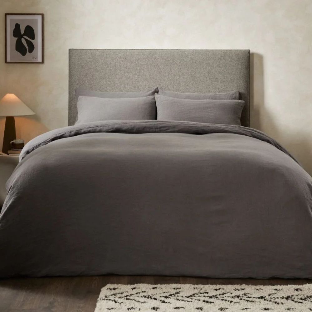 Soverom med naturlig stil og oppredd seng med dynetrekk i dyp charcoal farge