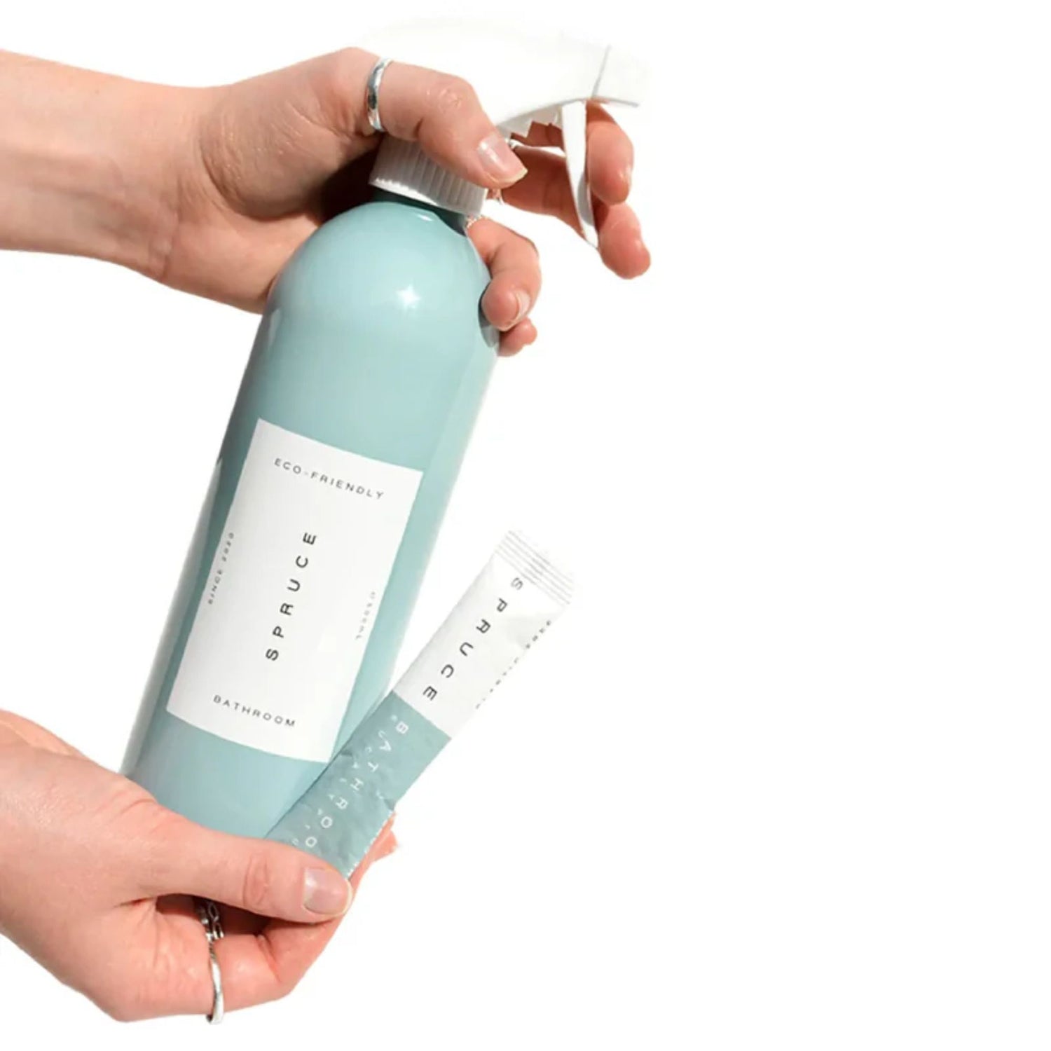 Hånd som fyller Spruce baderomsspray i gjenbrukbar aluminiumsflaske med plastfri refill.