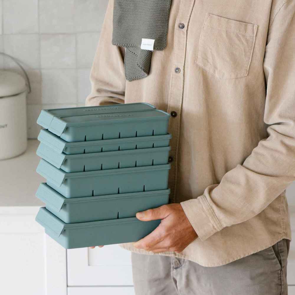 Person holder stablede silikonfryseformer i ulike størrelser med lokk i fargen Eucalyptus.
