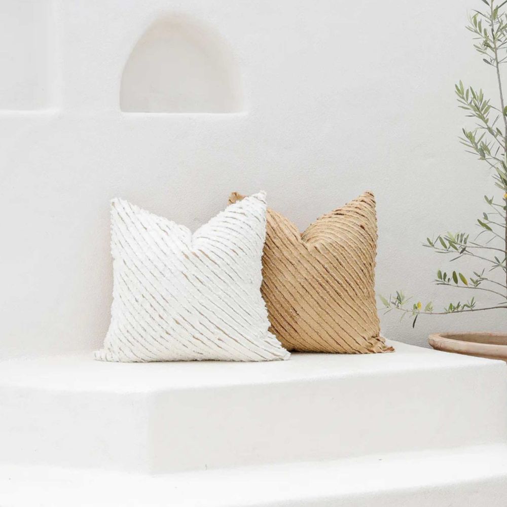 Stripete putetrekk i 100 % lin i hvit og beige fra MagicLinen, plassert på benk i lyst rom