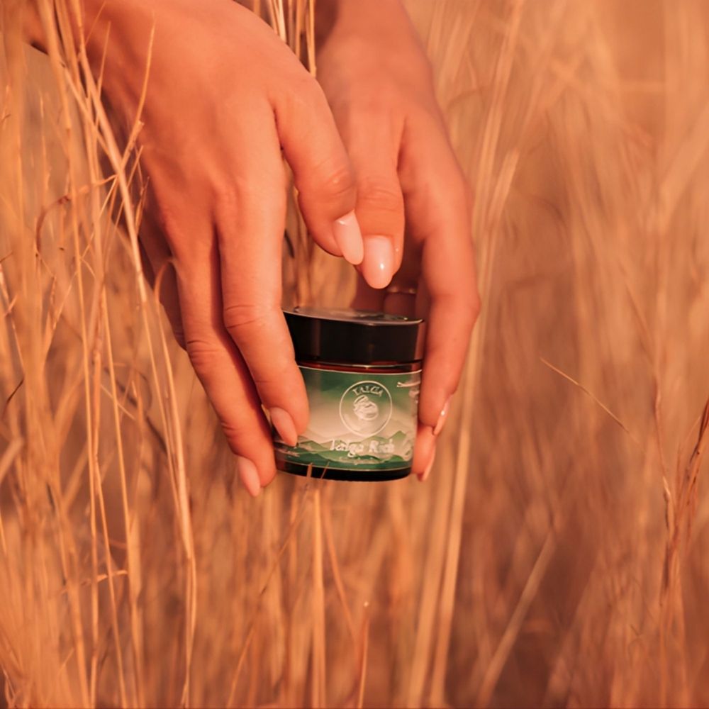 Hånd som holder Talga Rich ansiktskrem i naturlige omgivelser, norskprodusert talgbasert hudpleie i plastfri glasskrukke.