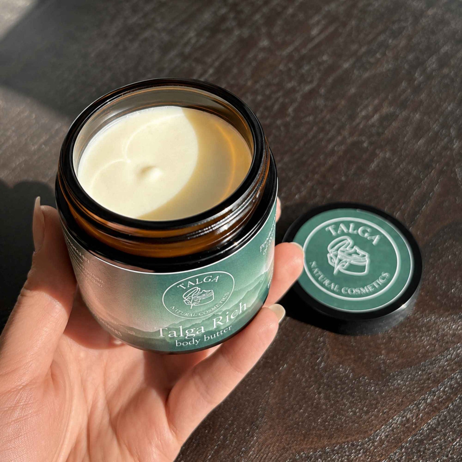 Talga Rich Body Butter holdt i hånden med kremet tekstur og naturlig lys. Vannfri og parfymefri kroppskrem laget med gressforet norsk talg.