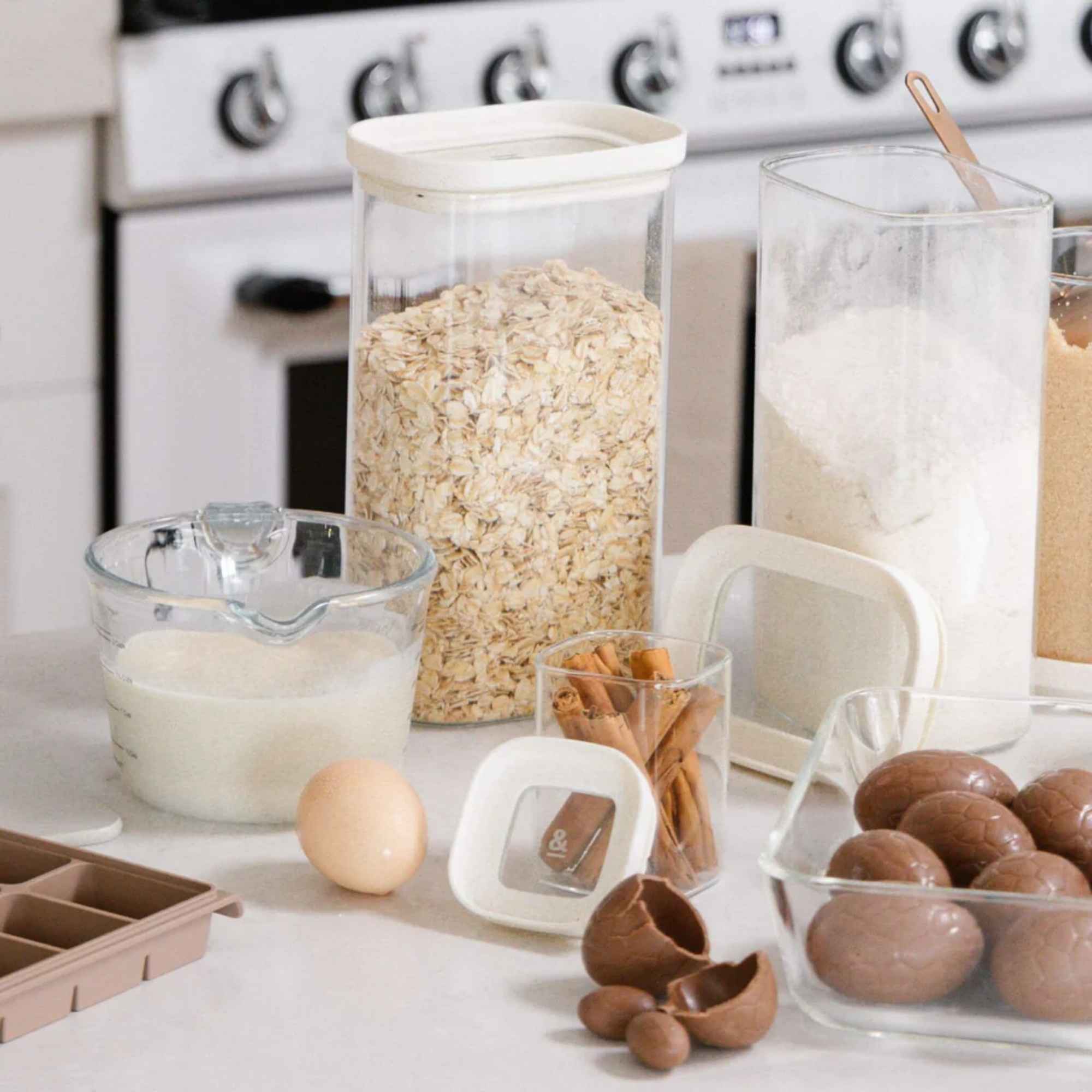 Havre, mel og egg klart til baking med glassbeholdere i bakgrunnen