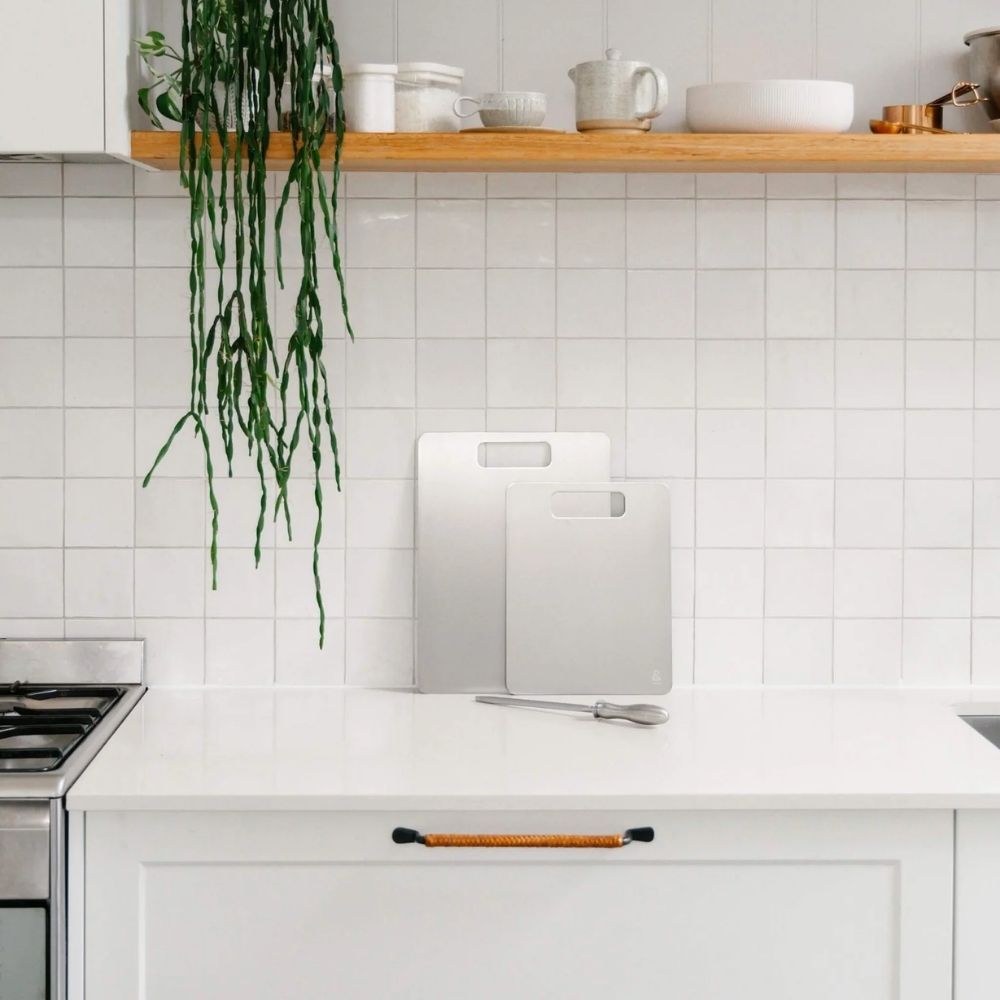 To skjærefjøler i titan plassert på kjøkkenbenk i lyst og minimalistisk kjøkken