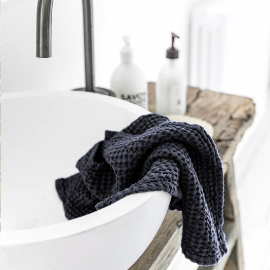Mørkegrått vaffelvevd kjøkkenhåndkle i lin og bomull fra MagicLinen lagt over vask.