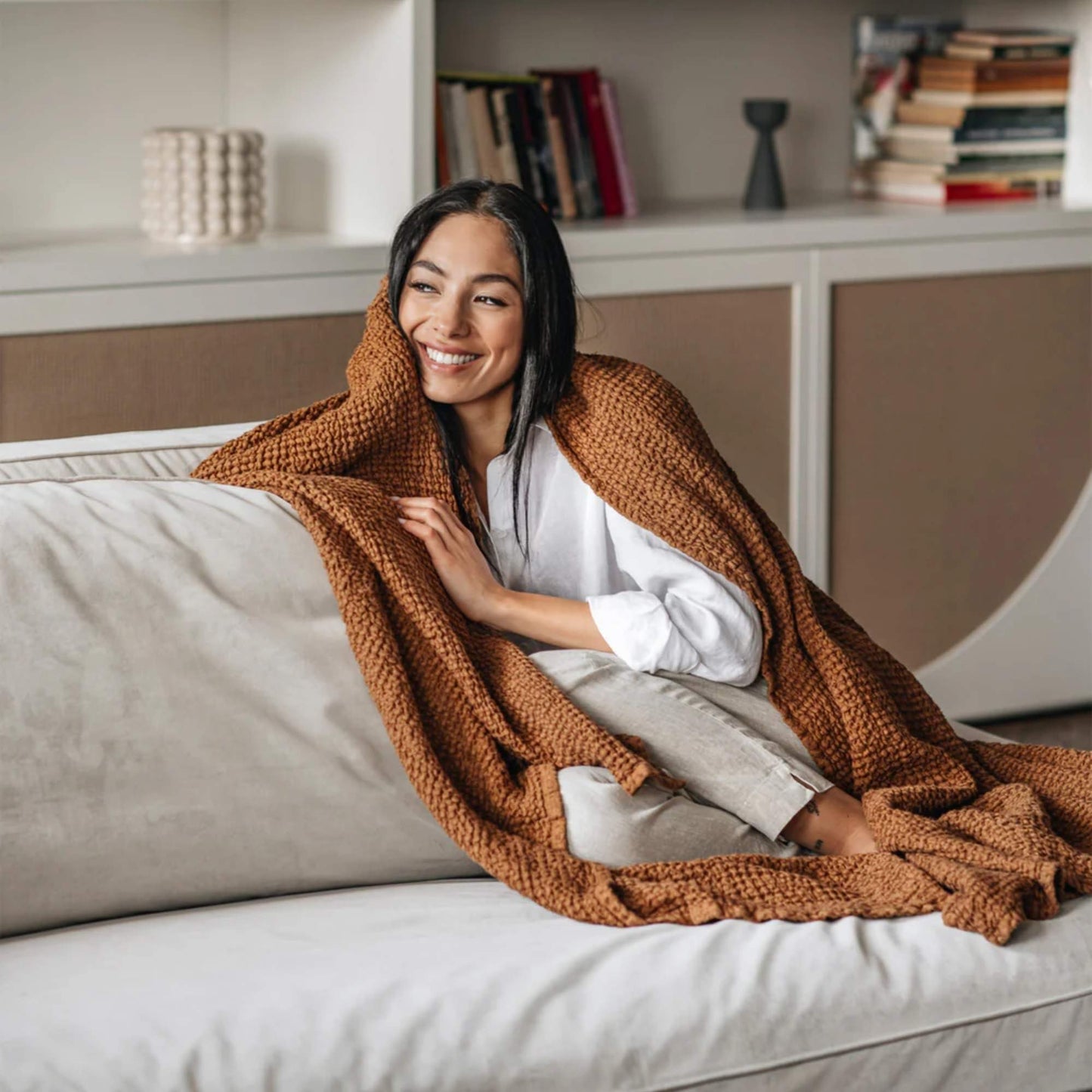 Kvinne med waffle-pledd i naturlig lin og bomull i fargen cinnamon fra MagicLinen, brukt som varm og pustende innpakning.