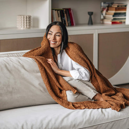 Kvinne med waffle-pledd i naturlig lin og bomull i fargen cinnamon fra MagicLinen, brukt som varm og pustende innpakning.