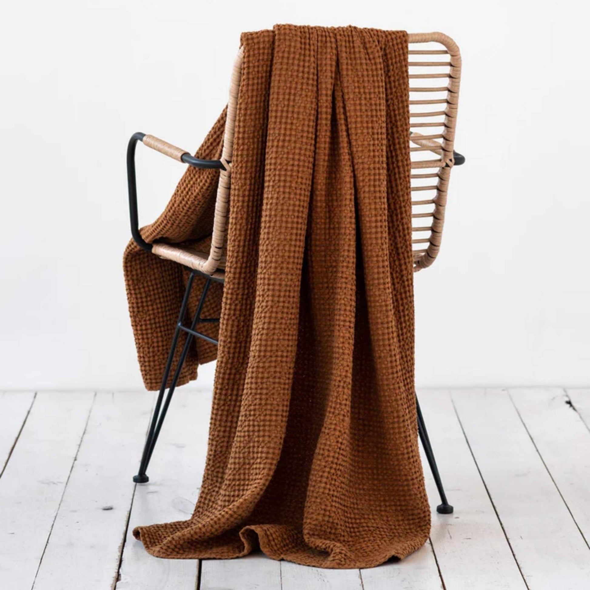 Waffle-pledd i lin og bomull i fargen cinnamon fra MagicLinen, lagt over en stol for å vise tekstur og naturlig varme i interiøret.