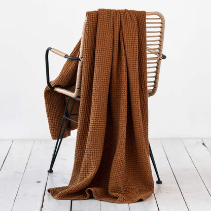 Waffle-pledd i lin og bomull i fargen cinnamon fra MagicLinen, lagt over en stol for å vise tekstur og naturlig varme i interiøret.
