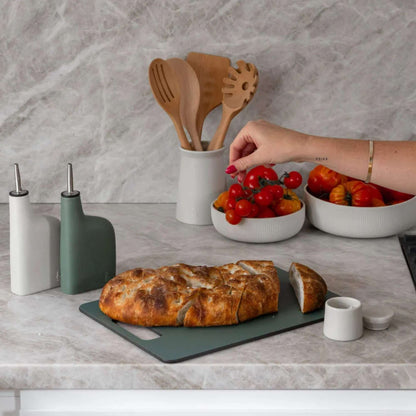 Wood fibre skjærefjøl i fargen Eucalyptus brukt til å skjære brød på kjøkkenbenk.