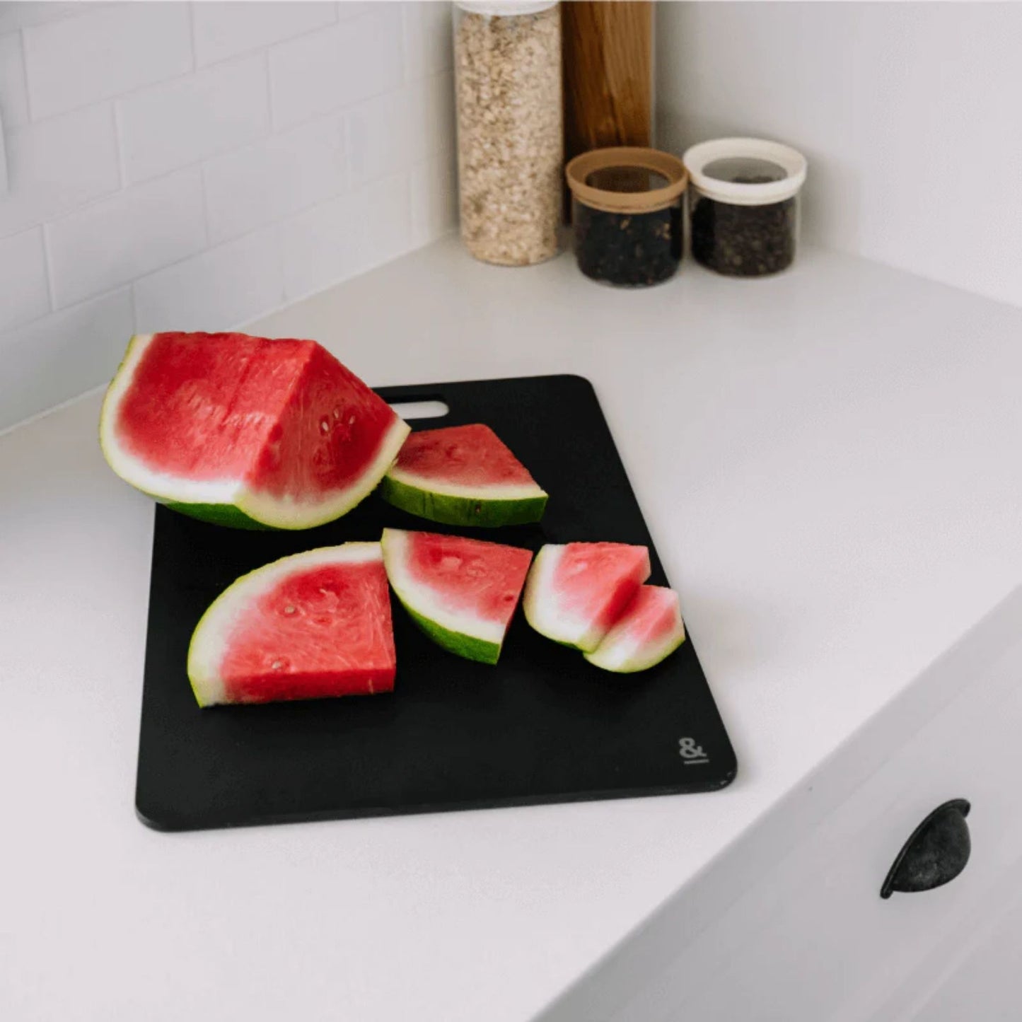 Wood fibre skjærefjøl i fargen Liquorice med oppskåret vannmelon på kjøkkenbenk.