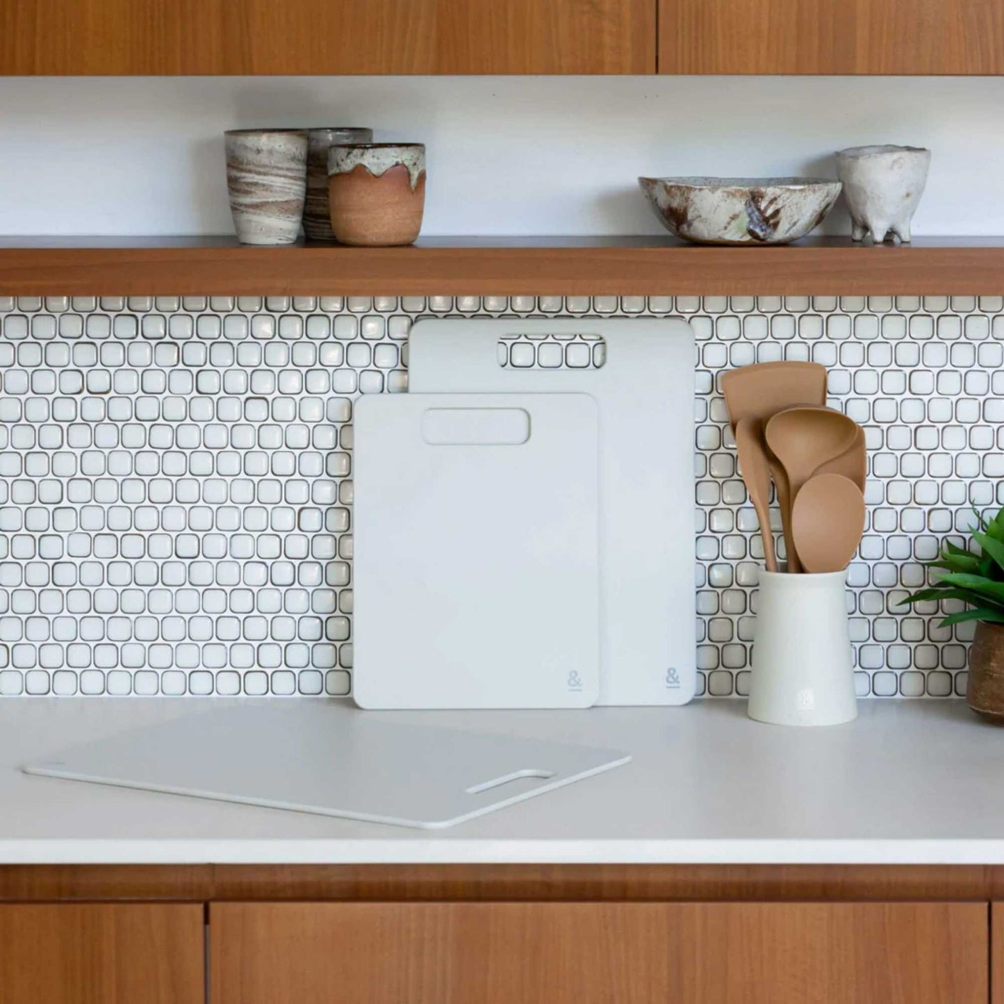 Wood fibre skjærefjøl i fargen Mushroom stående på kjøkkenbenk foran kjøkkenfliser.