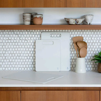 Wood fibre skjærefjøl i fargen Mushroom stående på kjøkkenbenk foran kjøkkenfliser.