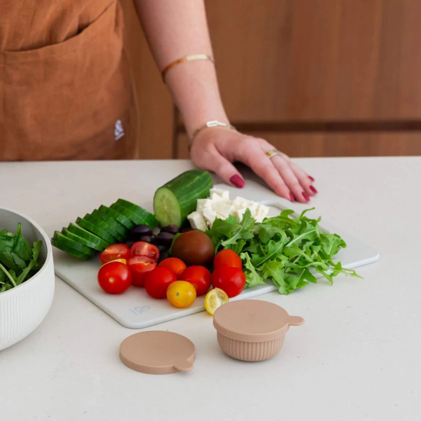 Wood fibre skjærefjøl i fargen Mushroom brukt til å kutte agurk, tomater og grønnsaker på kjøkkenbenk.